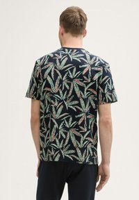 Korte mouwen, marineblauw T-shirt met een groen en rood bladerenpatroon, gemaakt van een zachte, lichte stof. Casual pasvorm, minimale naaddetails.