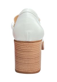 Talons blancs en cuir avec un dos arrondi, dotés d'un talon bloc en bois texturé avec des lignes horizontales et un minimum de détails de couture.