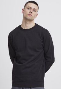 Felpa nera a girocollo, realizzata in tessuto morbido, con maniche lunghe e una vestibilità comoda, caratterizzata da un design semplice e senza pattern visibili.