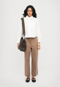 White cropped button-up shirt, brown wide-leg trousers, black structured flat shoes, and a black textured shoulder bag with a woven strap.