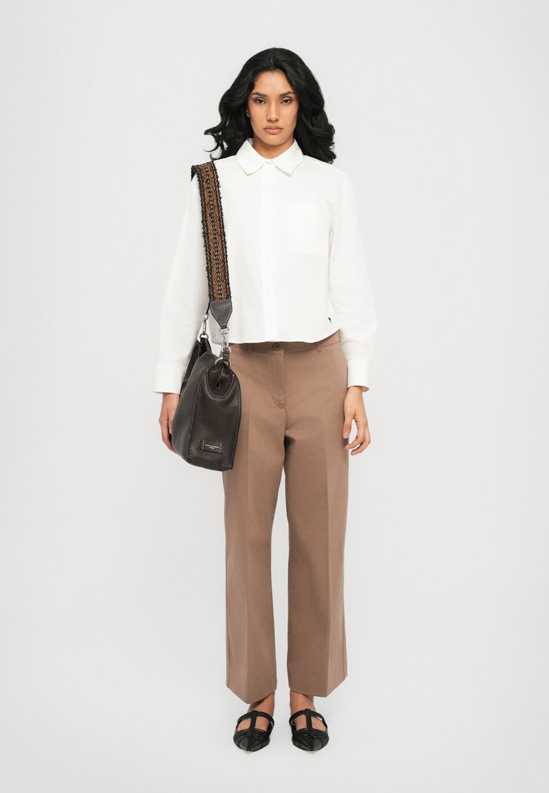 White cropped button-up shirt, brown wide-leg trousers, black structured flat shoes, and a black textured shoulder bag with a woven strap.