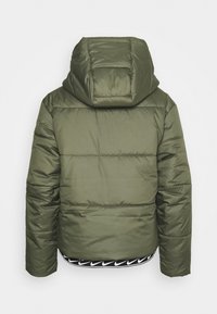 Chaqueta de plumón verde oliva con capucha, con textura acolchada, puños elásticos y un dobladillo negro con patrón y detalle de logo.