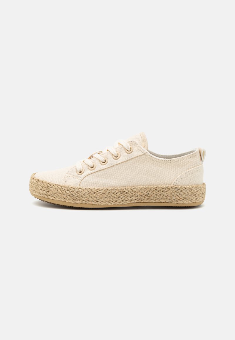 Sneaker in tela beige con punta rotonda, chiusura con lacci sulla parte anteriore e una suola intermedia in juta intrecciata. Presenta una texture liscia e un design minimalista.