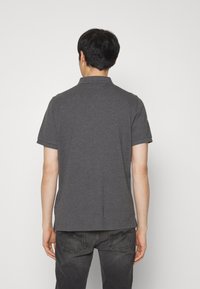 Polo gris avec col et manches courtes, fabriqué en tissu léger et lisse. Il présente un ourlet droit et des coutures minimales.