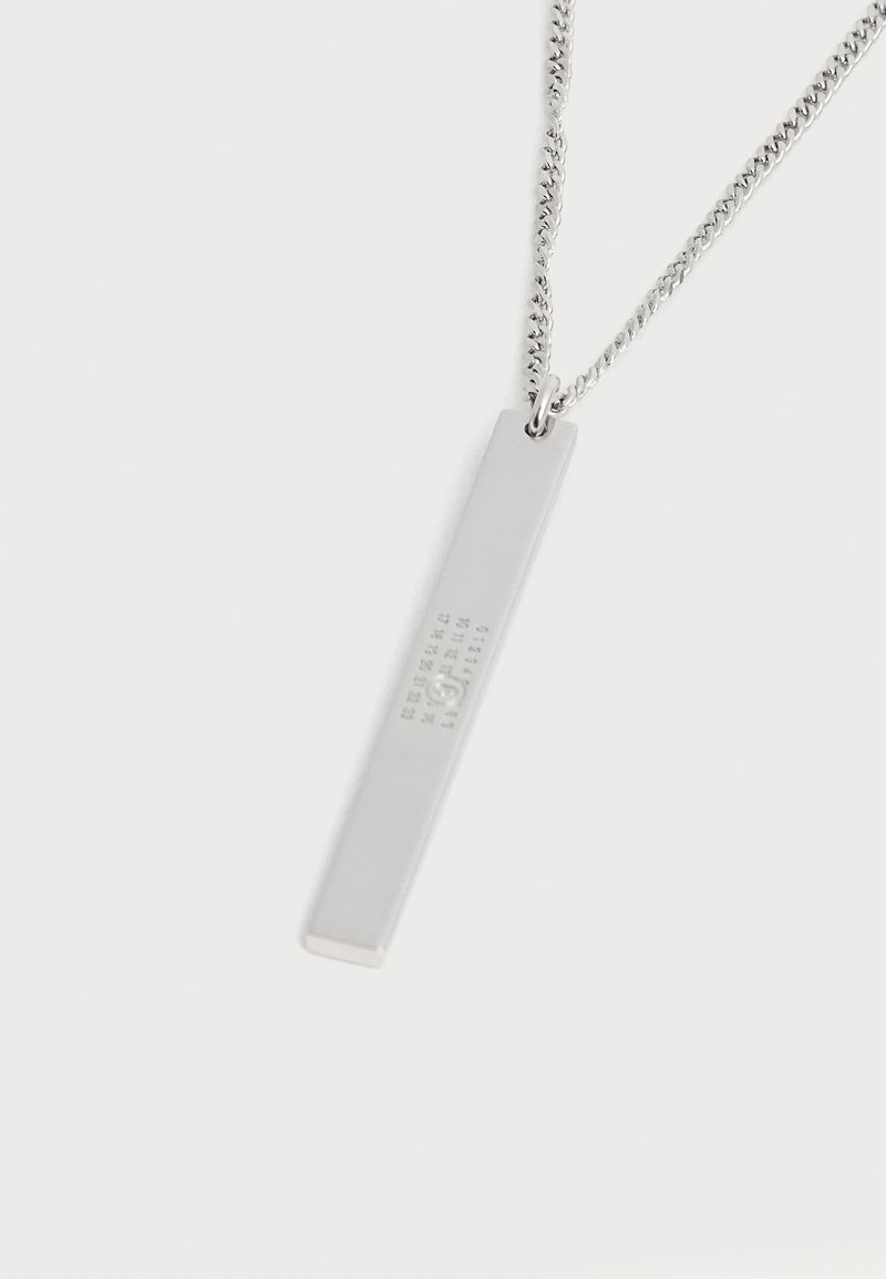 Ciondolo rettangolare in argento su una catena in argento con piccoli numeri in rilievo e design circolare su sfondo bianco.
