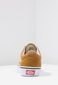 Tan suède sneakers met witte accenten, lage instapdesign, contrasterende stiknaden en een rode rubberen logo hieltab. Witte zool voor grip.