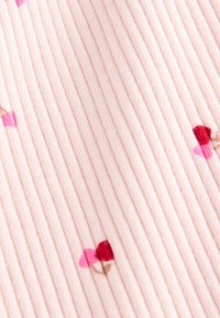 Tissu côtelé rose doux avec de petits motifs de fleurs rouges et roses répartis uniformément sur le matériau.