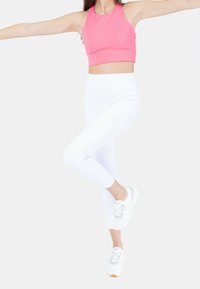 Rosa crop top, vita leggings och sneakers med grå detaljer. Outfiten har en åtsittande design och mjukt, elastiskt material.