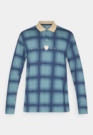 Dlouhý rukáv polo triko Nike Golf v modrém gradientu s mřížkovým vzorem, se světlobéžovým límcem a bílým logem na hrudi.