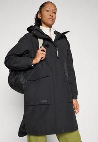 Zwarte waterdichte parka met een capuchon, elastische manchetten en meerdere zakken. Voorzien van een rits aan de voorkant en gemaakt van slijtvaste, duurzame stof.