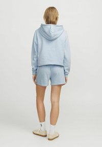 Haut en coton bleu clair avec capuche à cordon, associé à un short assorti. Le sweat a un design court et des poignets côtelés.