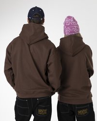 Sudaderas marrones con capuchas grandes, vistas por detrás y llevadas por dos personas. Una de ellas lleva un gorro de punto con un patrón rosa; la otra tiene una gorra azul. Pantalones negros con bolsillos traseros que muestran "JACKER" en amarillo.