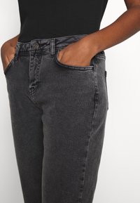 Svarta denimjeans med slim fit, med framfickor, klassisk knappstängning och subtila sömnadsdetaljer. Slät textur.