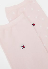 Ružové ponožky s bielymi bodkami, s malým logom v červenej, bielej a modrej farbe. Mäkký materiál s rebrovaným lemom.