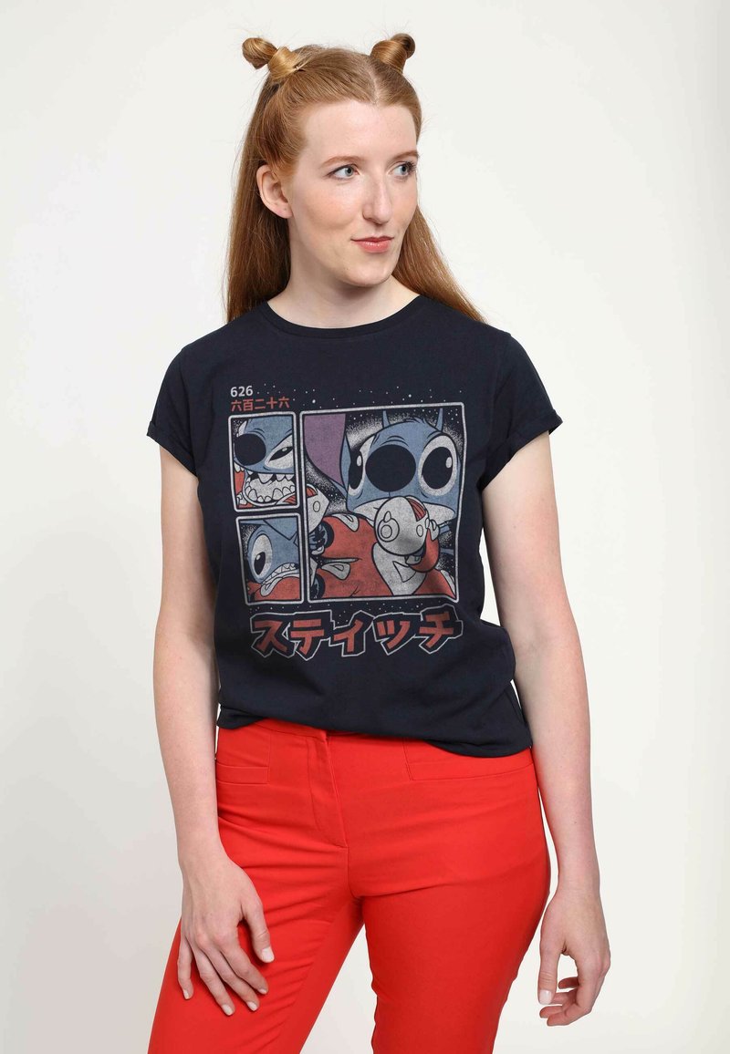 Schwarzes T-Shirt mit einem grafischen Druck von Cartoonfiguren, kurzen Ärmeln, Rundhalsausschnitt, getragen mit roten Hosen.