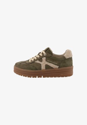 Groene suède sneaker met beige nepbontaccenten, crème veters en een bruine rubberen zool. Beschikt over een gestructureerd patroon op het bovenwerk.