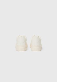 Witte sneakers met een gladde leren afwerking, ronde neus, platte zool en een reliëfmerk op de hiel. Minimalistisch ontwerp.