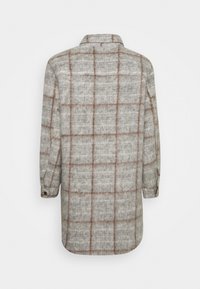 Grå flannel skjorte med et brunt ternet mønster, knaplukning ved ærmerne og klassisk krave; bagpå ses en buet kant og blød tekstur.