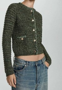 Cardigan vert en maille avec un motif texturé, col rond et boutons dorés. Comprend une poche avant avec un détail tressé.