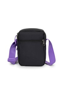 Sort firkantet crossover taske med en lilla justerbar rem. Har en lynlåslomme foran og struktureret stof. Kompakt design.