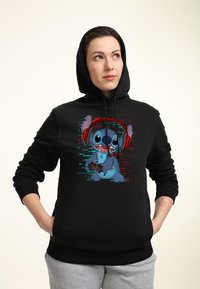Felpa nera con un grafico di un personaggio blu che indossa cuffie rosse e tiene un controller di gioco, con accenti di glitch digitale.