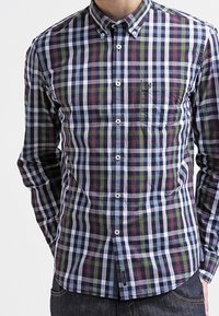 Langärmliges kariertes Hemd in Marineblau, Grün, Rot und Weiß; mit einem Button-Down-Kragen, einer Brusttasche und weißen Knöpfen.