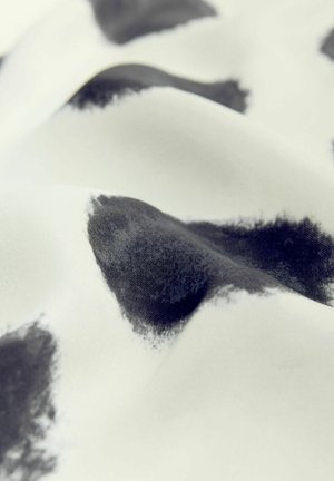 Textil cu o finisare netedă, mată, având o bază albă și modele neregulate de pete negre, creând un contrast subtil în textură.