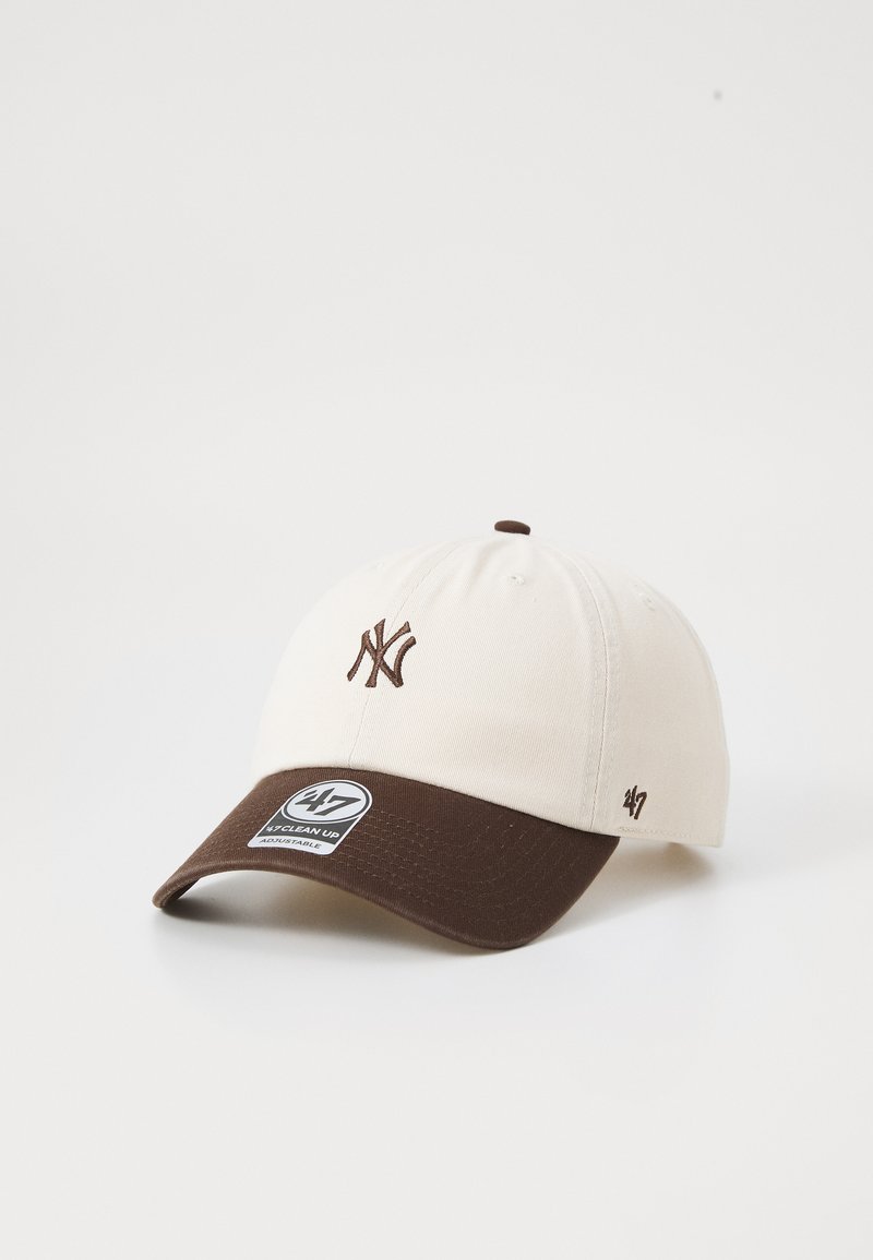 Beige katoenen baseballpet met een bruine klep, voorzien van een geborduurd NY-logo in bruin en een zwart-witte merklabel aan de voorkant.