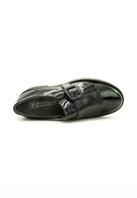 Zapato de cuero negro con un acabado brillante, que presenta una correa con hebilla y flecos decorativos en la parte superior, diseño de punta redonda.