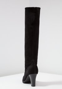 Botte haute jusqu'au genou en daim noir avec un talon effilé, une texture lisse et des accents de coutures minimales. Présente un bout arrondi.