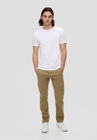 Weißes Baumwoll-T-Shirt, beige Baumwollhose und weiße Sneakers. Einfaches Design mit klassischer Passform und ohne sichtbare Muster oder Akzente.