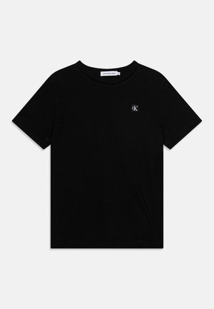 T-shirt noir à manches courtes et col rond avec petit logo blanc Calvin Klein "cK" sur la poitrine gauche et étiquette de la marque à l'intérieur du col.