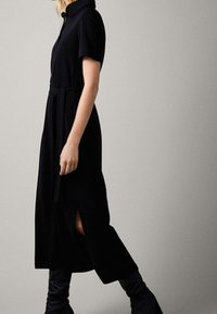 Sort, kortærmet kjole med krave, A-linjeform, sideslids og bælte i taljen, lavet af glat, let stof.