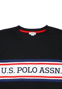 Svart bomull t-shirt med ett vitt, rött och marinblått band över bröstet med "U.S. POLO ASSN." tryckt i fet stil. Röd halsringning som accent.