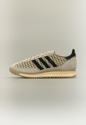 Sneaker Adidas beige e nero a quadretti con strisce nere, punta e tallone in camoscio e suola beige rigata, vista di lato.