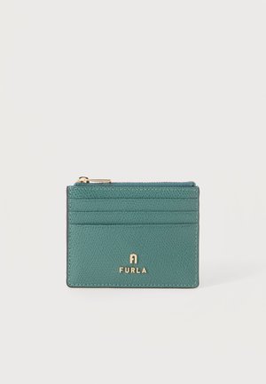 Porte-cartes en cuir bleu sarcelle avec quatre emplacements pour cartes, une fermeture éclair dorée et logo Furla embossé en or sur le devant.