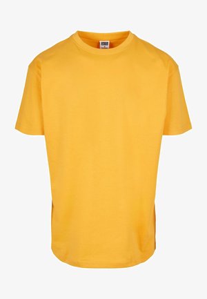 Žuta pamučna majica s okruglim izrezom i kratkim rukavima. Ima opušteni kroj i ravni rub. Bez uzoraka ili vidljivih dodataka.