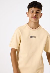 Korte mouwen, lichtgele t-shirt van katoen, met een bedrukte logo met de woorden "ENERGETIC REWIND" op de borst.