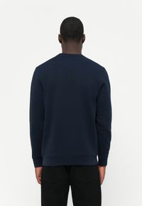 Navy blue sweatshirt with long sleeves and crew neck. Soft texture, ribbed cuffs and hem. Simple design, no visible patterns or hardware.