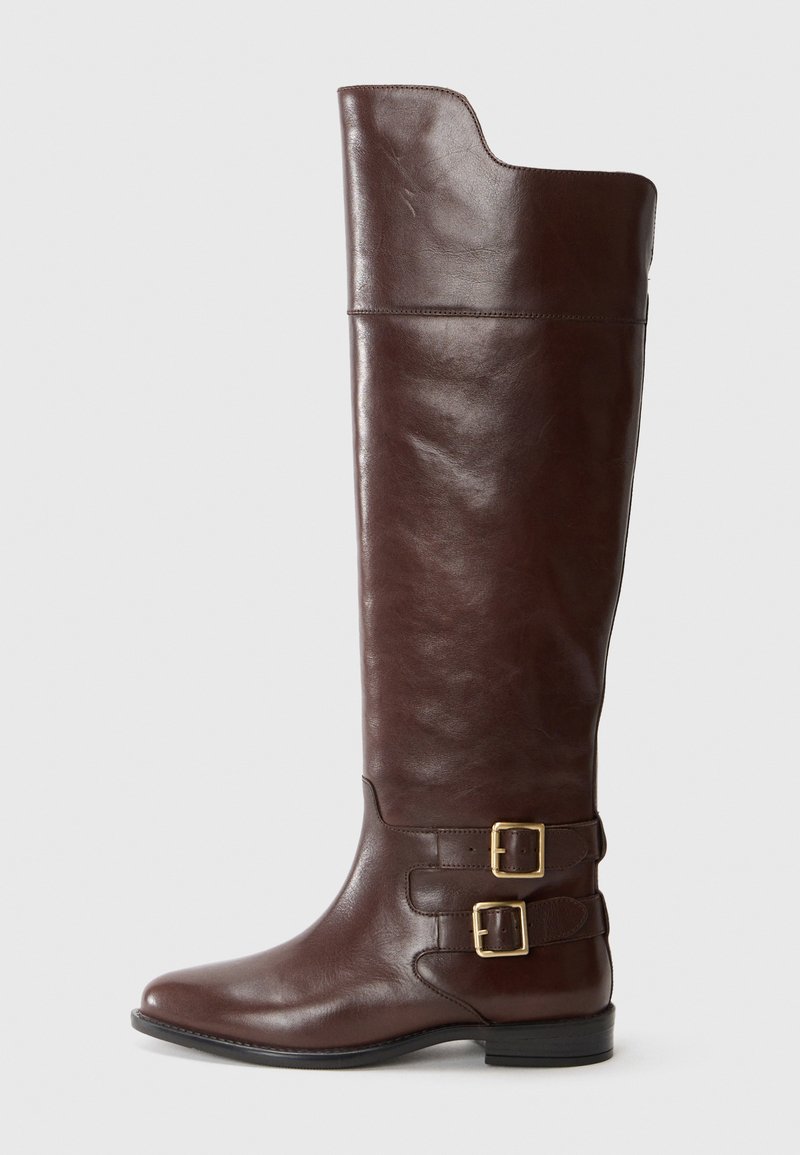 Brown leather knee-high boot with a rounded toe, featuring two gold-tone buckles at the ankle and a smooth, polished texture.