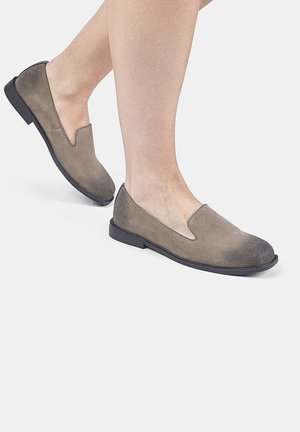 Scarpe slip-on grigie in suede con punta arrotondata, suola in gomma nera bassa e un taglio a V ai lati, che mostrano un gradiente di texture morbido.