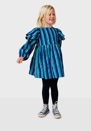 Robe rayée bleu et vert avec des manches bouffantes et une jupe évasée, associée à des leggings noirs et des baskets bleues.