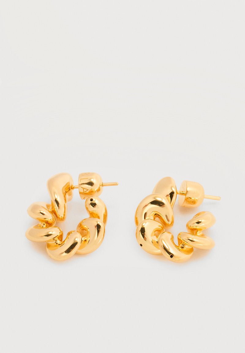 Σκουλαρίκια κρίκοι σε χρυσό τόνο με χοντρή, σπειροειδή σχεδίαση και κούμπωμα με καρφί, πάνω σε απλή λευκή επιφάνεια.