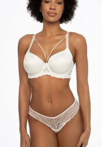 Biały koronkowy zestaw bielizny składający się z gładkiego, wyściełanego biustonosza z krzyżującymi się ramiączkami oraz dopasowanego, przezroczystego koronkowego Stringa z falbaniastymi brzegami.