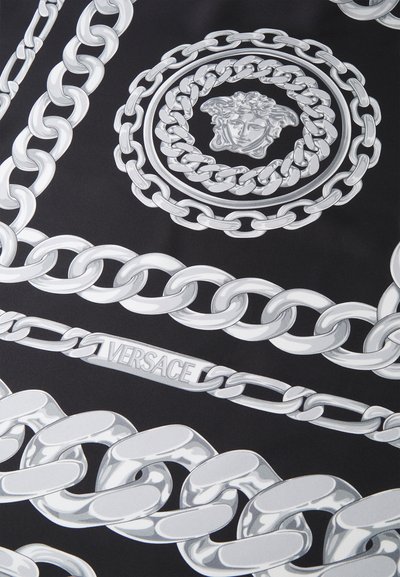 Juodas audinys su dideliais sidabriniais grandinėlės raštais, įskaitant centrinį apvalų motyvą su veidu ir juostą su užrašu "VERSACE".