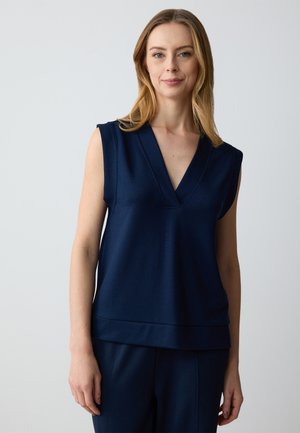 Top senza maniche blu navy con scollo a V profondo e ampie cuciture sulle spalle, realizzato in tessuto liscio, con una vestibilità leggermente ampia e orlo.