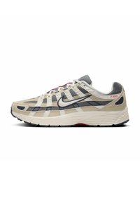 Beige running shoe with gray mesh and suede details, white accents, black sole, red branding, and unique crosshatch design on the upper.