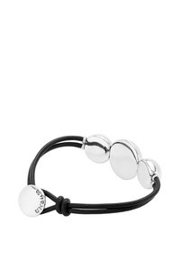 Pulsera de cuentas plateadas sobre una banda elástica negra, con cuentas metálicas lisas y redondeadas y un acabado pulido. Diseño ajustable.