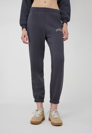 Pantaloni sportivi grigio scuro con polsini elasticizzati, con logo ricamato "PHOENIX" sulla coscia sinistra. Realizzati in tessuto morbido, ideali per il tempo libero.