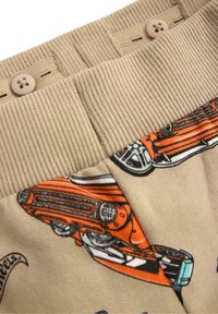 Beige bomuldsstof med en ribbet talje med knapper og et farverigt vintage bilprint i orange og sort.